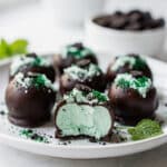 Creamy mint Oreo truffles with a glossy chocolate shell on marble.