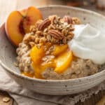 Creamy peach cobbler protein oats in a rustic ceramic breakfast bowl.
