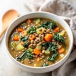 Crockpot vegetable lentil soup with carrots kale and tomato broth in bowl