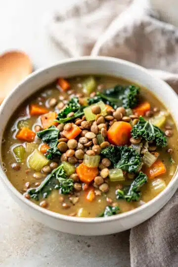 Crockpot vegetable lentil soup with carrots kale and tomato broth in bowl