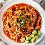 Slow cooker salsa chicken in a warm tortilla with avocado and cilantro