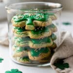 Vibrant green shamrock sugar cookies with glossy icing and festive sprinkles.