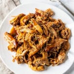 Slow cooker honey garlic chicken in glossy sauce on white ceramic bowl