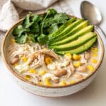 Creamy slow cooker white chicken chili in a white ceramic bowl with cilantro garnish.