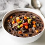 Smoky black bean soup recipe in a rustic bowl with fresh garnishes