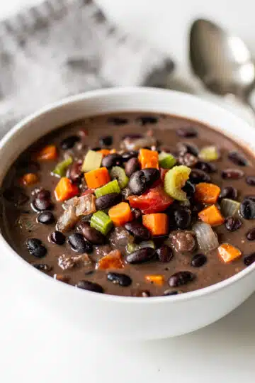 Smoky black bean soup recipe in a rustic bowl with fresh garnishes