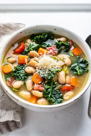 Creamy white bean kale soup recipe in a rustic bowl with parmesan