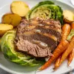 Beer braised corned beef cabbage plated in rustic ceramic bowl on wood table