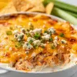 Creamy buffalo chicken dip with shredded chicken and melted cheese in ceramic dish