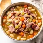 Hearty ham and bean soup recipe in a rustic ceramic bowl.