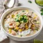Creamy slow cooker white chicken chili with avocado and cheese topping