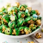 Leprechaun Popcorn recipe with green toffee and rainbow sprinkles in bowl.