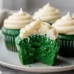 Green velvet cupcakes with cream cheese frosting on a rustic wood background.