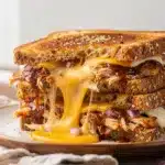 Grilled barbecue chicken grilled cheese sandwich sliced open on rustic board