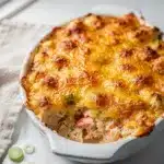 Creamy hot crab dip with crispy cheese topping on rustic bread board