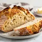 Freshly baked Irish Soda Bread with raisins on a rustic wooden cutting board.