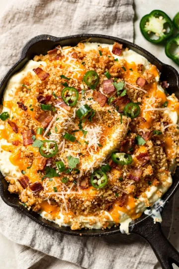 Creamy jalapeno popper dip with crispy bacon panko topping in cast iron skillet.