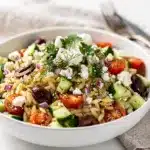 Lemon orzo spring salad with feta, tomatoes, and fresh herbs in bowl.