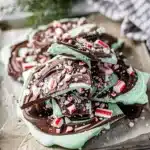 Homemade mint chocolate bark with crunchy candy pieces on rustic wood.