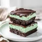 Close up of fudgy mint chocolate brownies with creamy mint and glossy ganache topping