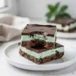 Layered mint chocolate cookie bars with creamy filling and glossy chocolate topping.