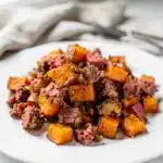 Crispy corned beef hash with sweet potatoes and red peppers in cast iron skillet