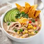 Creamy white chicken chili with beans corn avocado and cilantro topping