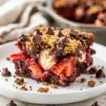 Strawberry chocolate dump cake slice with ice cream on white plate