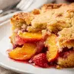 Rustic strawberry peach dump cake with golden crumble topping in ceramic dish.