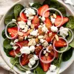 Vibrant strawberry spinach salad with feta and almonds in a rustic bowl.