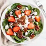 Fresh strawberry spinach salad with candied pecans and feta cheese in a bowl.