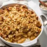 Homemade apple cinnamon crumble with creamy filling and crispy oat topping.