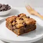 Golden brown butter blondies with melted chocolate chips on a marble countertop.