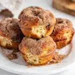 Cinnamon sugar donut muffins on a white plate with cinnamon sticks.