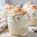 Coconut cream pie jars with layers of crust pudding and toasted coconut