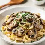 Creamy mushroom alfredo pasta with fettuccine in a glossy cheese sauce.
