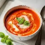 Creamy tomato basil soup with fresh herbs in a rustic bowl