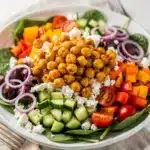 Crispy chickpea Greek salad with feta, tomatoes, cucumbers, olives, and spinach.