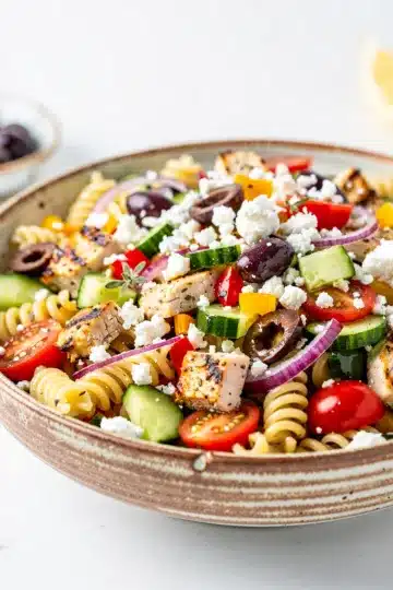 Greek chicken pasta salad with cucumber olives feta in Mediterranean style plating