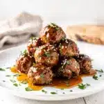 Honey garlic meatballs in a glossy sticky sauce on a white plate