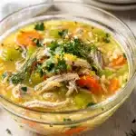 Creamy lemon chicken orzo soup in a white bowl with fresh dill garnish.