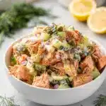 Lemon dill salmon salad recipe with creamy dressing and fresh vegetables in a bowl.