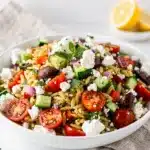Colorful Mediterranean orzo salad with fresh vegetables olives and feta cheese