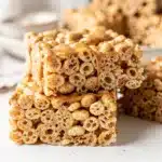 Peanut butter rice krispie treats with chocolate drizzle and peanuts.