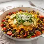 Savory beef taco skillet with melted cheese and fresh avocado toppings.