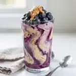 Creamy blueberry banana protein smoothie topped with almond butter and chia seeds