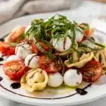 Colorful caprese tortellini pasta salad with fresh mozzarella and basil.