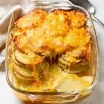 Cheesy scalloped potatoes casserole with crispy cheese edges and creamy sauce.