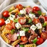Colorful Italian pasta salad with pepperoni, cheese, and fresh vegetables in a bowl.