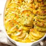Creamy cheesy scalloped potatoes recipe in a rustic ceramic baking dish